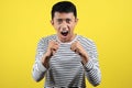 Young Asian man doing angry gesture, annoyed, and emotional, isolated on yellow