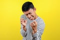 Young Asian man doing angry gesture, annoyed, and emotional, isolated on yellow