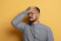 Young Asian Man Doing Facepalm Gesture While Standing Isolated Over Yellow Background