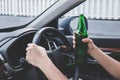 Young asian man drives a car with drunk a bottle of beer behind the wheel of a car