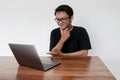 Young Asian man feeling happy and smile when work laptop on table. Indonesian man wearing blue shirt Royalty Free Stock Photo