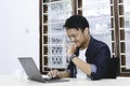 Young Asian man feeling happy and smile when work laptop on table. Indonesian man wearing blue shirt