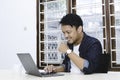 Young Asian man feeling happy and smile when work laptop on table. Indonesian man wearing blue shirt