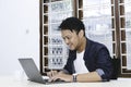 Young Asian man feeling happy and smile when work laptop on table. Indonesian man wearing blue shirt