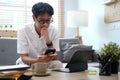 Young asian man freelancer working online at home with computer tablet and using smart phone Royalty Free Stock Photo