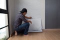 Young Asian man glueing wallpapers on the wall at home.