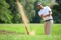 Young Asian man golfer hitting a bunker shot Royalty Free Stock Photo