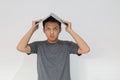 Young Asian man in grey t-shirt Feeling stress and confuse with laptop in his head. Frustrated and stressed young man with work Royalty Free Stock Photo
