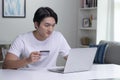 Asian man holding credit card and using laptop computer. Businessman working at home.Online shopping, e-commerce, internet banking Royalty Free Stock Photo