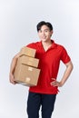 Young asian man holding delivery package looking positive and happy standing and smiling with a confident smile showing teeth Royalty Free Stock Photo
