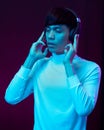 Young asian man listening music with headphone in neon light. Royalty Free Stock Photo