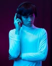 Young asian man listening music with headphone in neon light.