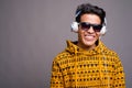 Young Asian man listening to music against gray background Royalty Free Stock Photo