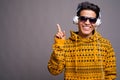 Young Asian man listening to music against gray background Royalty Free Stock Photo