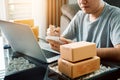 Young asian man looking on computer laptop and writing order list on paper, SME concept Royalty Free Stock Photo