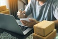 Young asian man looking on computer laptop and writing order list on paper, SME concept