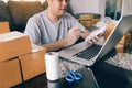 Young asian man looking on computer laptop and writing order list on paper, SME concept Royalty Free Stock Photo