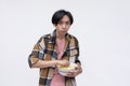 A young asian man looking spooked while holding a bowl of popcorn. Isolated on a white background Royalty Free Stock Photo