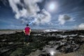 Surreal night scene of traveler looking up into the sky. Bright moonlit landscape