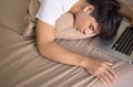 Young asian man lying in bed over his laptop Royalty Free Stock Photo