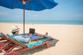 Young Asian man using laptop on beach bench Royalty Free Stock Photo