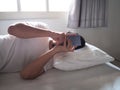 Young Asian man with mobile smart phone lying down on the bed. Royalty Free Stock Photo