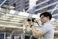 Young asian man photographer holding camera to taking picture of city view. Outdoor summer lifestyle portrait traveler having fun Royalty Free Stock Photo