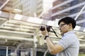 Young asian man photographer holding camera to taking picture of city view. Outdoor summer lifestyle portrait traveler having fun Royalty Free Stock Photo