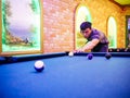 Young Asian man play billiards in the colorful club - Aiming white ball to shot Royalty Free Stock Photo