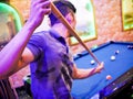 Young Asian man play billiards in the colorful club - Aiming white ball to shot