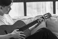 Young asian man playing guitar while sitting on sofa in living room Black and white He love playing guitar Composing and thinking Royalty Free Stock Photo