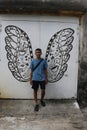 Young Asian man posing in front of 2 wings