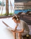 Young asian man reading book and listening to music by the pool Royalty Free Stock Photo