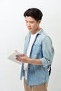 Young Asian man reading book and wearing casual clothing with backpack over white background Royalty Free Stock Photo