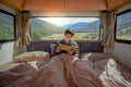 Young Asian man reading magazine book in camper van Royalty Free Stock Photo