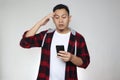 Young Asian man reading texting chatting  on his phone, shocked worried surprised expression, over grey Royalty Free Stock Photo