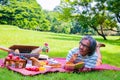 Young Asian man relax time in park.In the morning he is reading book with  red apply Royalty Free Stock Photo