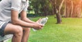 Young asian man runner relaxing holding drinking water bottle and sitting on bench in the park outdoors after sport at early Royalty Free Stock Photo