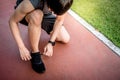 Young Asian man runner tying shoe laces on running trail Royalty Free Stock Photo