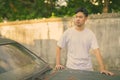 Young Asian man with rusty old car in the streets outdoors