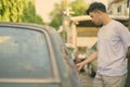 Young Asian man with rusty old car in the streets outdoors