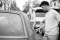 Young Asian man with rusty old car in the streets outdoors