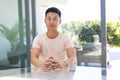 Young Asian man seated at a modern home office on a video call Royalty Free Stock Photo