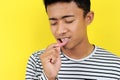 Young Asian man showing ulcer or blister in his mouth at camera, isolated on yellow Royalty Free Stock Photo