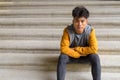 Young Asian man sitting with arms crossed on staircase in the city Royalty Free Stock Photo