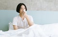 Young Asian man sitting on bed holding tissue handkerchief blowing running nose feels unwell unhealthy. Sick man having influenza Royalty Free Stock Photo