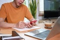 Young man sitting in living room and using smart phone and laptop computer. Royalty Free Stock Photo