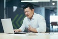 A young Asian man is sitting in the office, holding his chest, feeling pain, having a stroke Royalty Free Stock Photo