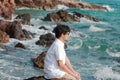 Young Asian man sitting on the rock and looking at far away Royalty Free Stock Photo