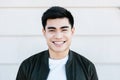 Young asian man smiling confidently at camera while standing on city street Royalty Free Stock Photo